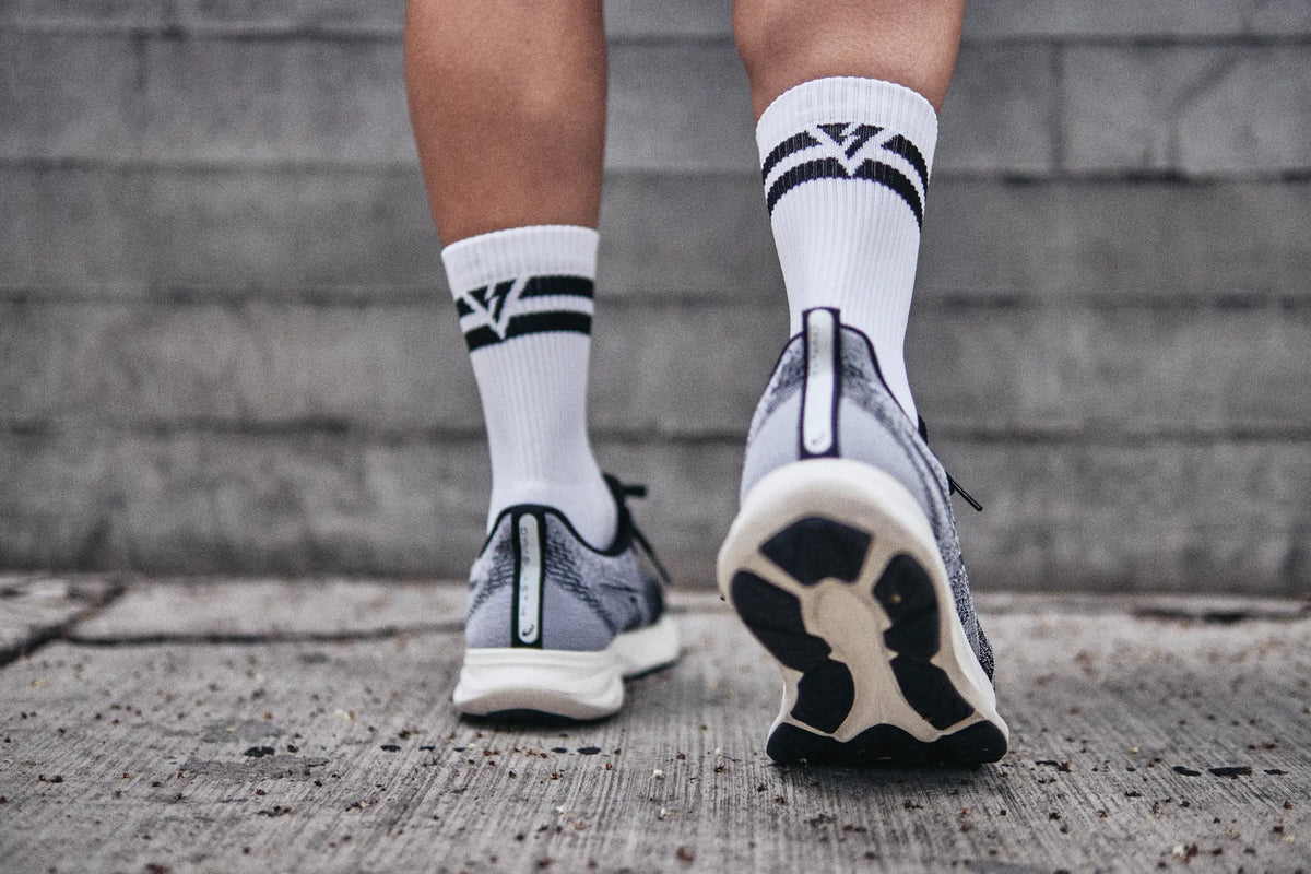 Calcetas deportivas antiampollas VEROZ blancas con logotipo negro, con tenis para correr
